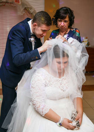 Lutsk, Volyn / Ukraine - September 16 2018: Mother and groom take off bride veil after weddingのeditorial素材