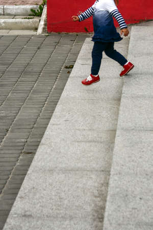 Closed up little girl down stone staircase outdoorsの写真素材