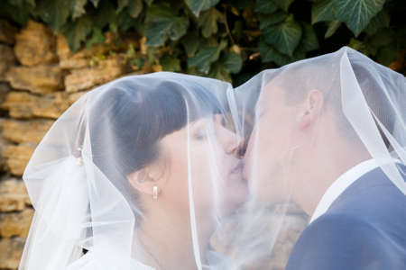 Lutsk, Volyn / Ukraine - September 30 2018: Bride and groom kissing under veil in parkのeditorial素材