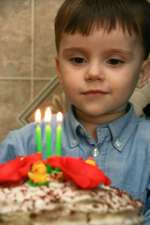 3-year-old caucasian boy celebrating his birthday and blowing candles on cake