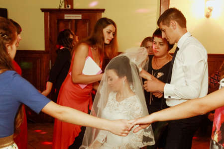 Goloby, Volyn / Ukraine - September 20 2015: Mother and groom take off bride veil after weddingのeditorial素材
