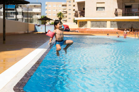 La Manga, Murcia / Spain - July 28 2018: Cute young boy jumping into a swimming pool while on a fun vacationのeditorial素材