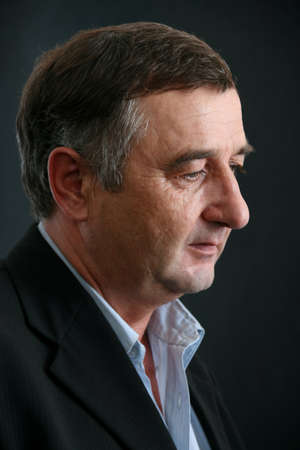 Lutsk, Volyn / Ukraine - May 18 2012: Close up side profile photo of middle age man wear casual suit posing on dark background. Shallow depth of field.のeditorial素材