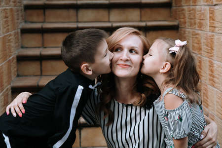 Lutsk, Volyn / Ukraine - September 07 2019: Little girl and boy kissing their mother on streetのeditorial素材