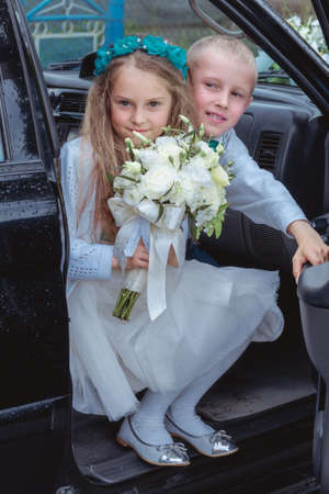 Maryanivka, Volyn / Ukraine - May 21 2017: Little girl with a bouquet and boy posing in carのeditorial素材