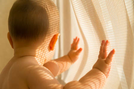 Creative portrait of a child with a pattern of lights and shadows on his face created to pass sunlight through a net at balcony. Shallow depth of field.の写真素材