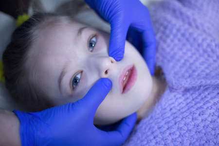 Lutsk, Volyn / Ukraine - November 15 2017: Hands of a masseur in gloves make a massage of a child faceのeditorial素材