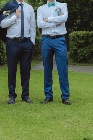 Young groom posing with his friend in park at springtimeの写真素材