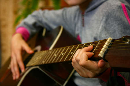 Close up of a teen musician playing acoustic guitar. Shallow depth of field