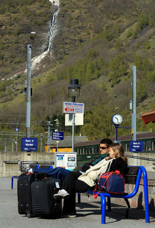 Flam, Norway - May 04 2007: Couple of traveler tourists with suitcases sitting on a bench and waiting to board a train at the railway stationのeditorial素材