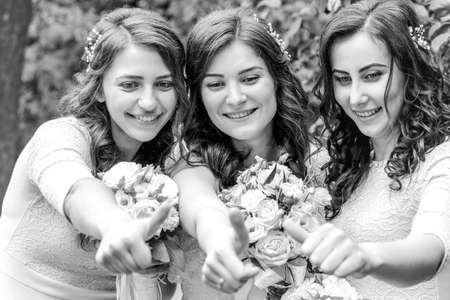 Maryanivka, Volyn / Ukraine - May 21 2017: Caucasian bride and two bridesmaids showing thumb up on open air. Shallow depth of field.のeditorial素材