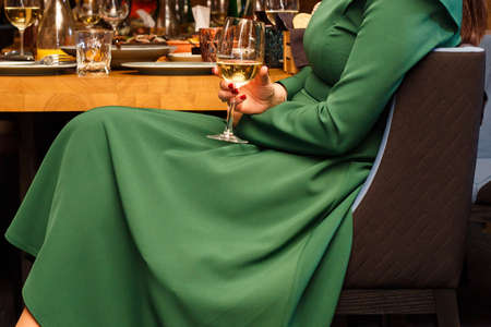 Stylish woman posing with glass of wine in hand at restaurantの写真素材