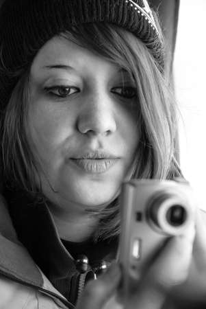 Bukovel, Frankivsk / Ukraine - March 09 2012: Young woman taking photo to compact camera. Shallow...