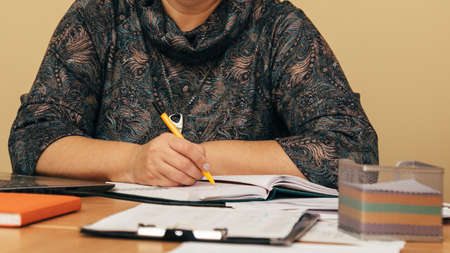Woman freelancer female hands with pen writing on notebook at home or office. Shallow depth of field.の写真素材