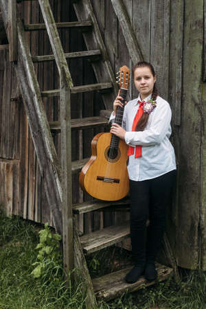Rokyni, Volyn / Ukraine - May 29 2019: Young musician with guitar posing next to old wooden staircaseのeditorial素材