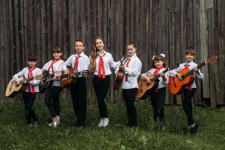 Rokyni, Volyn / Ukraine - May 29 2019: Female music teacher and pupils posing with guitars next to wooden wallのeditorial素材