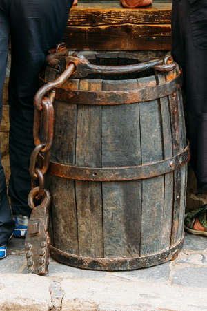 Vintage wooden barrel or bucket with rusty chain and load on wall backgroundの写真素材
