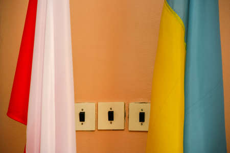 Switches on a wall and flags of Poland and Ukraine