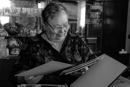 Novograd, Volyn / Ukraine - April 01 2009: Senior female with family photo album posing at table at...