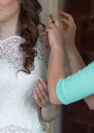 Bride friend are helping to dress her before weddingの写真素材