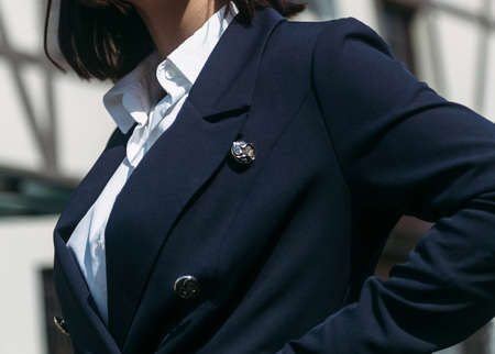 Fashionable young woman in an elegant jacket and white shirt is posing near a building in the summer dayの写真素材