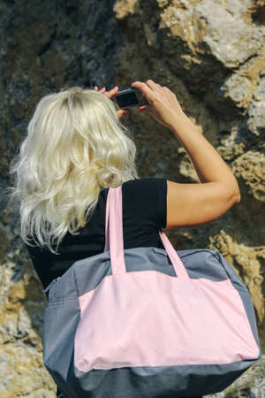 Female tourist taking photo with compact camera, enjoying mountains landscapeの写真素材