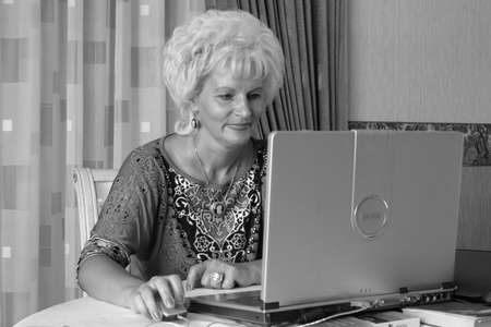 Kovel, Volyn / Ukraine - August 13 2010: Middle aged woman sitting at table using computer.