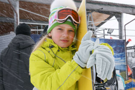 Bukovel, Frankivsk / Ukraine - March 06 2010: Girl in ski glasses with snowboard posing next to lift on snowy dayのeditorial素材
