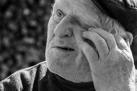 Lutsk, Volyn / Ukraine - April 03 2009: Senior man with closed eyes, touches the head with one handのeditorial素材