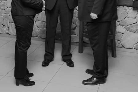 Cropped shot of woman and two businessman wearing office trousers and shoes standing on floorの写真素材