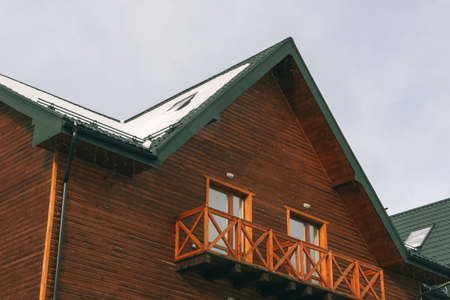 The facade of the second floor of the alpin wooden house with an open balcony in winter mountain...