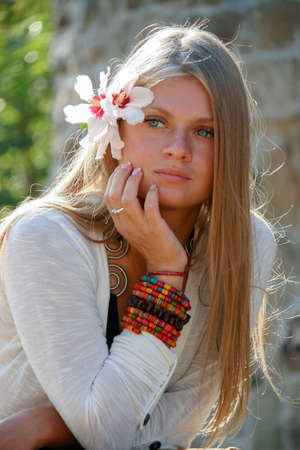 Sudak, Crimea / Ukraine - September 16 2011: Young woman with a flower in her hair posing against a wall on street in summerのeditorial素材
