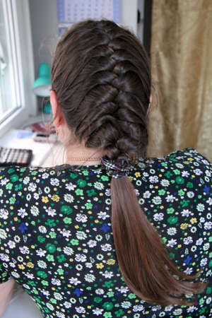 Back view of young unrecognizable woman with braided hair. Shallow depth of field.