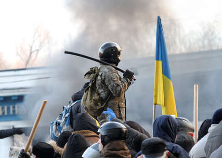 A man in a helmet with a stick next to the Ukrainian flag during Mass anti-government protests in the center of Kiev on Hrushevskoho St. near Dynamo Stadium in January 2014の写真素材
