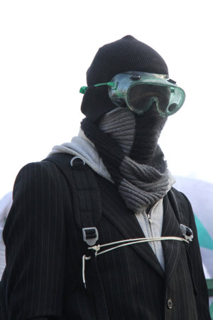 Man wearing suit and knitted hat and scarf and plastic protection safety goggles with backpackの写真素材