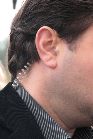 Male head with earphone in his ear at outdoor. Cropped view.