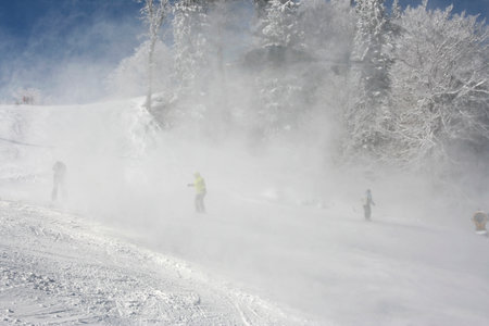 Tourist service helicopter taking off snow powder above slope at ski resortの写真素材