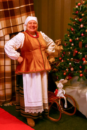 Kopachivka, Ukraine - December 09 2012: Senior woman in Ukrainian folklore costume posing next to the Christmas treeのeditorial素材
