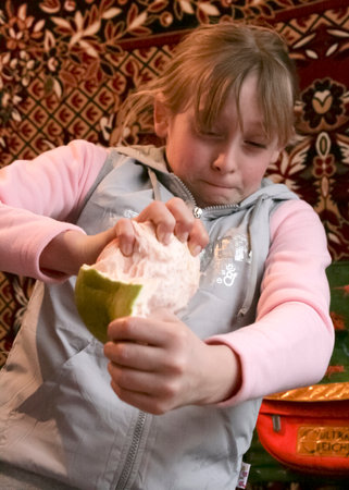 Volycia, Ukraine - March 21 2009: Preteen girl is peeling fresh pomelo. Healthy nutrition.のeditorial素材