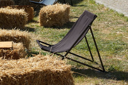 Folding chair next to hay bale on lawn yard for country party