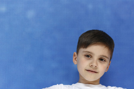 Portrait of a young boy with short hair on a blue background