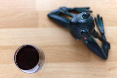 Meditating frog figurine in yoga position with red wine on floor. Symbolic concept is health and yoga. Shallow depth of field.の写真素材