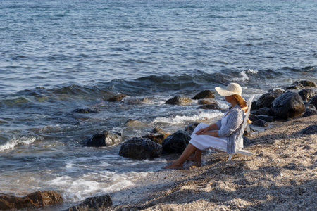 Woman sitting on a chair in front of ocean on beach. Summer holiday or vacation travel.の写真素材
