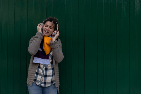 A young Latin American girl listens to music with her headphones, laughs, sings and has a good timeの写真素材