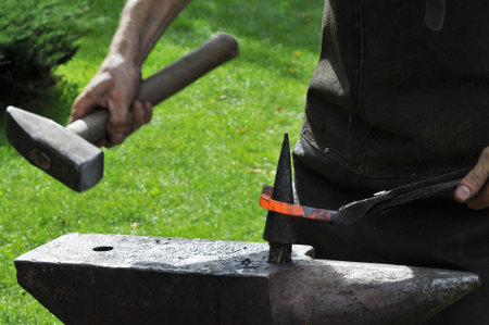 blacksmith working with hot metal on the anvil at a forgeの写真素材