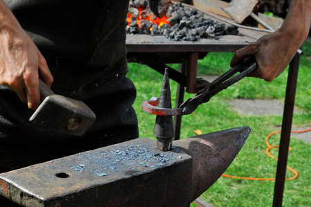blacksmith working with hot metal on the anvil at a forgeの写真素材