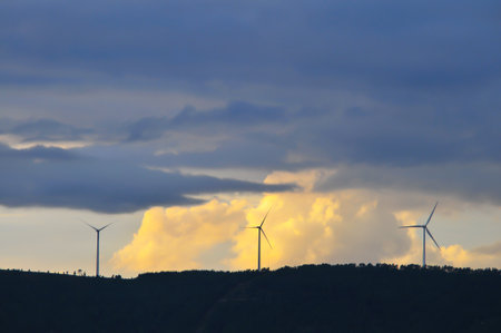 An image of wind turbines on a background of blue sky with clouds