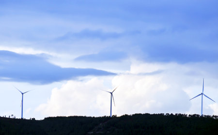 An image of wind turbines on a background of blue sky with clouds