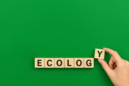 Wooden cubes spelling the word ECOLOGY, a hand completes the wordの素材