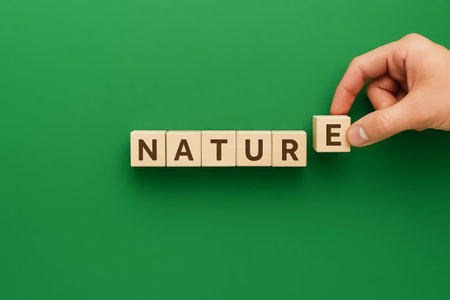 Wooden cubes spelling the word NATURE, a hand completes the wordの素材